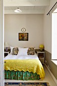 Double bed with yellow blanket and floral valance in simple bedroom