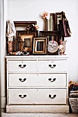 Many empty picture frames on white-painted vintage chest of drawers
