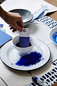 Woman's hand dipping paper gift tag in indigo dye