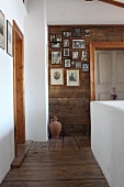 Landing with whitewashed, masonry balustrade and collection of photos on wooden wall