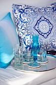 Drinks on tray in front of white and blue patterned cushions on bench