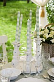 White and grey striped candles in white candlesticks between place settings