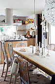 Langer Esstisch mit verschiedenen alten Stühlen vor Küchentheke
