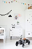 Retro-style, black toy car in white nursery with colourful bunting