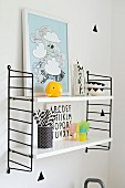 Framed picture and beaker of drinking straws on Sting shelving unit with black sides
