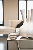 Designer vase with multiple necks on minimalist steel table, corner sofa in background