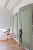Fitted wardrobes with green wooden doors and pink chair next to window