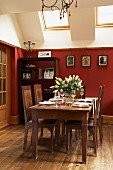 Traditional dining set and exotic-wood shelves against red-painted wall below skylights