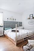Double bed with white metal frame and dog in dog basket in rustic bedroom