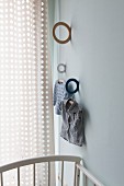 Ring brackets in different colours mounted on wall and child's clothing hung from wooden coat hanger