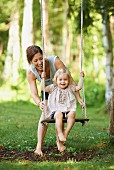 Mother with daughter on garden swing