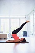 Woman performing exercises on yoga mat in living room