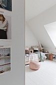 Pink pouffe next to bed in attic bedroom with white wooden floor