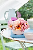 Arrangement of salmon-pink violas in china bowl on garden table