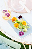 Sliced avocado arranged with spring onions and viola flowers