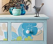 Blue chest of drawers decorated with floral wallpaper on front