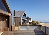 Camber Sands Beach Houses, Rye, United Kingdom. Architect: Walker and Martin, 2014; View along beach showing neighbouring beach houses.