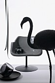 Still-life arrangement with silhouette of flamingo and camera on shell chair