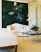 Weisses Sofa vor grossformatigem, modernem Bild, davor Couchtisch mit Steinplatte auf Gestell mit geschwungenen Beinen