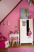 Weißer Kleiderschrank und Konsolentisch mit geschwungenen Beinen vor rosa getönter Giebelwand in Mädchenzimmer mit nostalgischem Flair