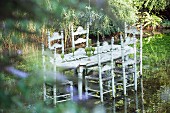 Set table and rush-bottom chairs standing in pond