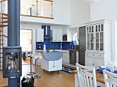 Skandinavische Küche mit Kücheninsel auf Rädern in offenem, Wohnraum; freistehender Schwedenofen im Vordergrund