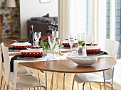 White shell chairs around table festively set with red bowls and black napkins