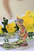 Vintage-style figurine of girl and narcissus flowers in glass bowl