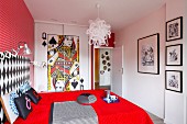 Bold, red bedroom with playing card motif on front of fitted wardrobes and gallery of black and white artworks