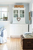White, country-house-style dresser and old trunk on wooden floor in rustic interior