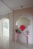 Rosafarbener Konsolentisch unter modernem Wandspiegel und Glasschiebetüren in elegantem Dielenbereich