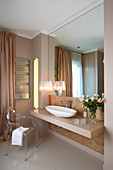 Luxuriöses Bad mit glänzender Waschtischplatte raumhohem Wandspiegel, Designer Tischleuchte und Ghost Stuhl