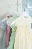 Pastel, ruched dresses on clothes hangers hung from bracket