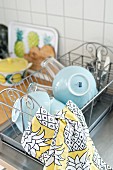 Blue bowls and patterned tea towel on draining rack next to sink
