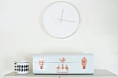 Purist wall clock above retro, suitcase-style bread bin and chain pot with graphical pattern