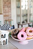 Iced donuts on cake stand and stacked coffee mugs