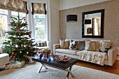 Geschmückter Weihnachtsbaum in Wohnzimmer, Couchtisch mit dunkler Tischplatte gegenüber Sofa in Zimmerecke und Bogenlampe