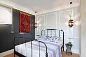 Double bed with black, metal lattice frame, Moroccan-style rug on dark grey wall and pendant lamp in bedroom