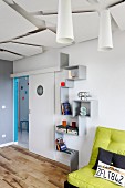 Zig-zag shelves between sliding door with porthole and green futon sofa
