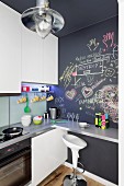 Designer bar stool at counter on chalkboard wall in fitted kitchen