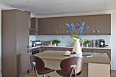 Modern kitchen in brown with blue flowers in a vase on island