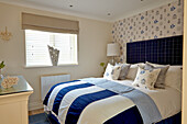 Bedroom with blue and white bed linens and patterned wallpaper