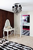 White, postmodern dressing table with vanity mirror and Ghost chair in front of brown curtain next to to open door with view into bathroom