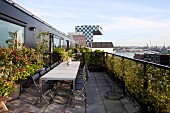 Row of tables and folding chairs on penthouse roof terrace with view of city
