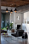 Living area with designer chairs, house plants and vintage pendant lamps in loft apartment