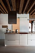 Kitchen island with corrugated metal fronts in loft-style apartment with rustic wooden ceiling