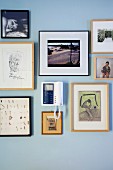 Collection of framed drawings and photos around intercom unit on wall painted pale blue
