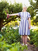 Blonde woman wearing striped dress holding freshly harvested beetroots
