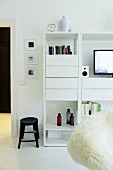 Black stool next to white shelves with drawer module