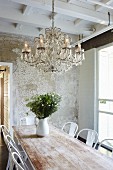 Dining set with classic chairs, bouquet in white jug and chandelier hung from wooden ceiling